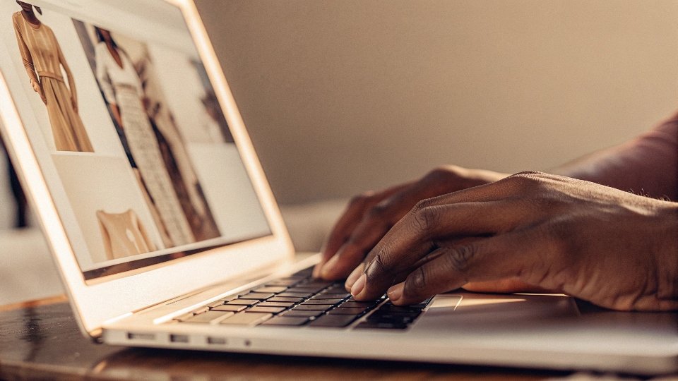 A person's hands typing on a laptop with the Alibaba website on the screen.