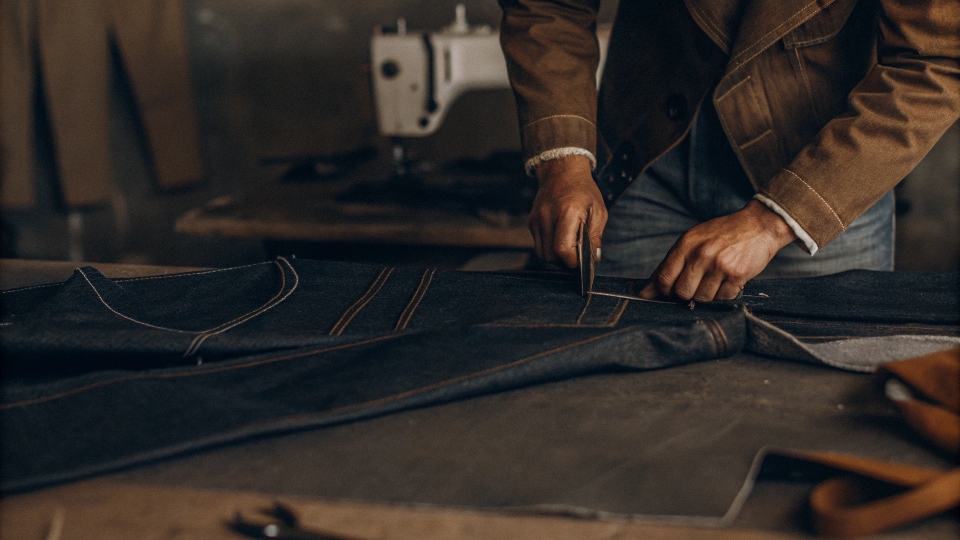 A tailor marking a pair of jeans to be tapered down the inseam for a stacked effect.