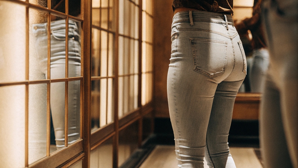 A person showing the perfect fit of stacked jeans at the waist while the legs are long.