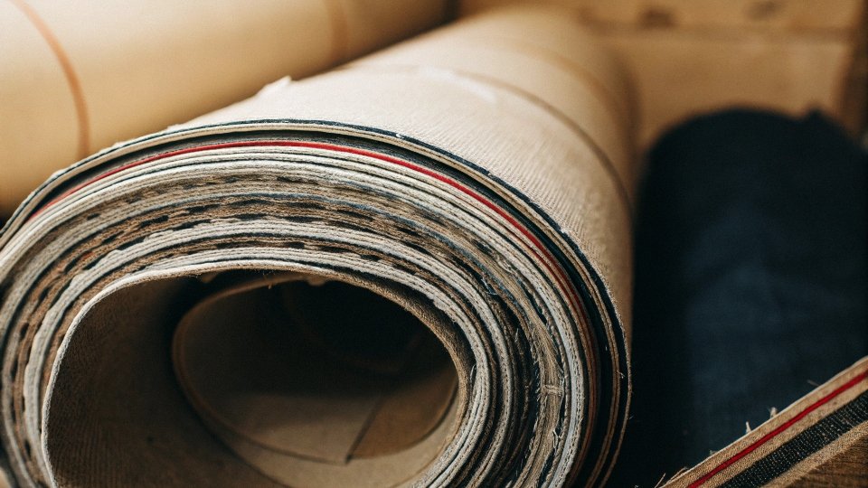 A roll of narrow selvedge denim with its iconic red-line edge shown.