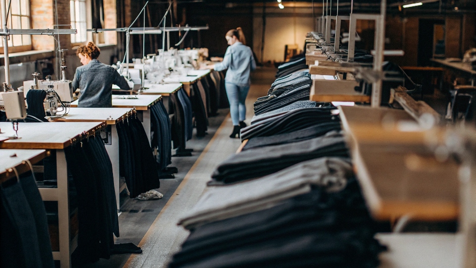 A factory floor with organized workstations and a quality control manager reviewing a product