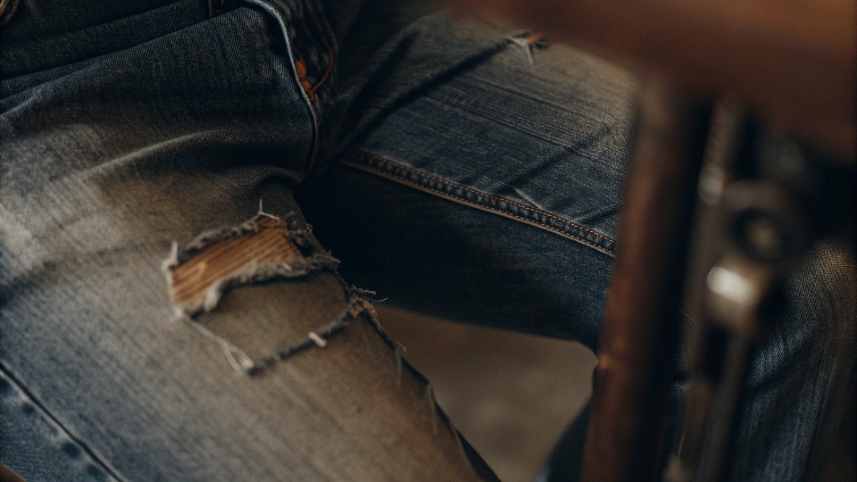 A macro photograph showing the individual, slightly frayed fibers of a well-worn denim fabric