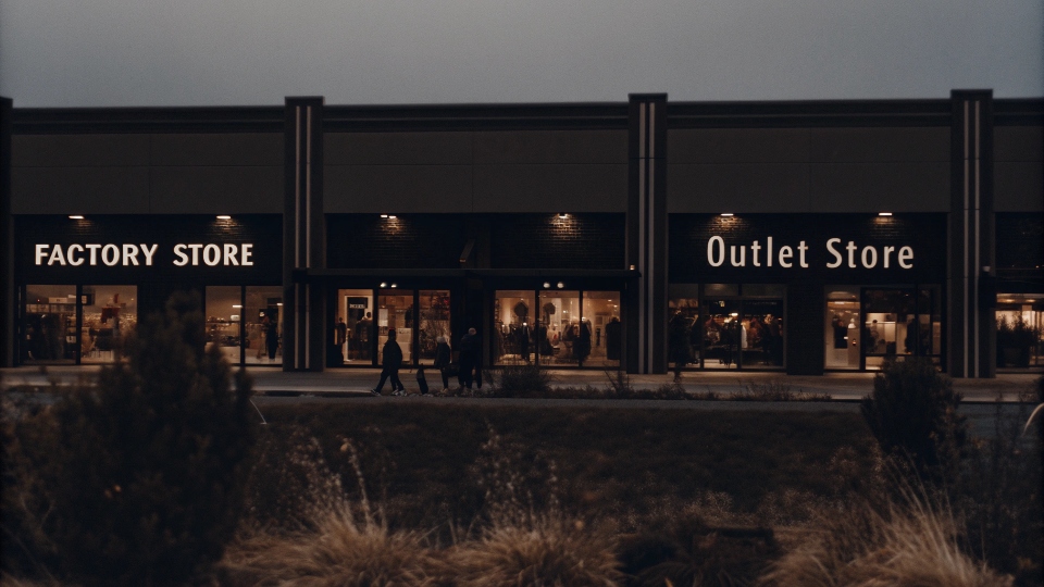 A modern outlet mall with signs for both "Factory Store" and "Outlet Store"