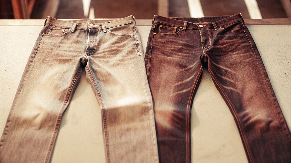 A pair of beautifully faded raw denim jeans showing the high-contrast wear patterns from infrequent washing