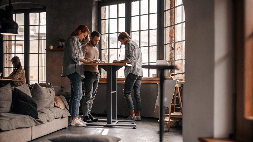 A modern, open-plan office with casually dressed employees collaborating around a table