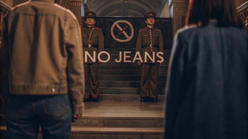 A propaganda-style poster in North Korea with people in uniform clothing, with a "no jeans" symbol over it