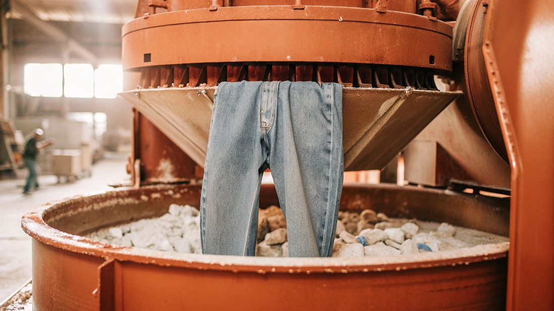 An industrial washing machine filled with denim and pumice stones.