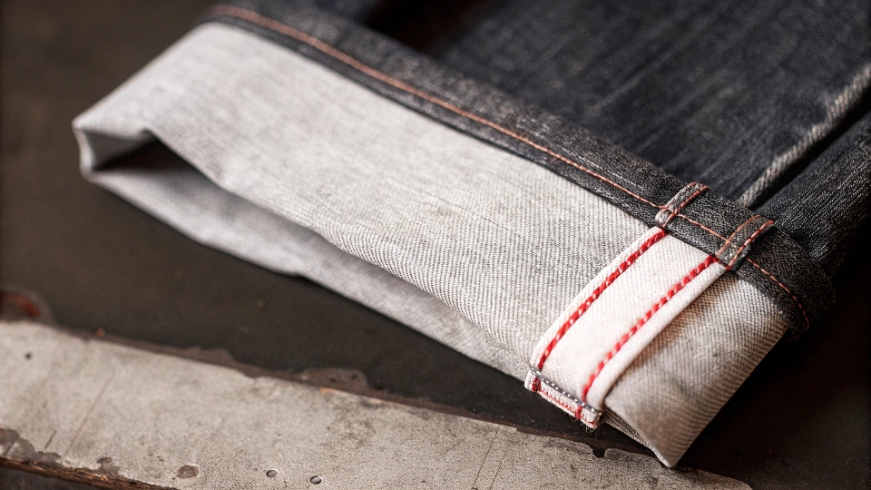 A close-up shot of the "self-edge" or "red ear" on a cuffed selvedge jean
