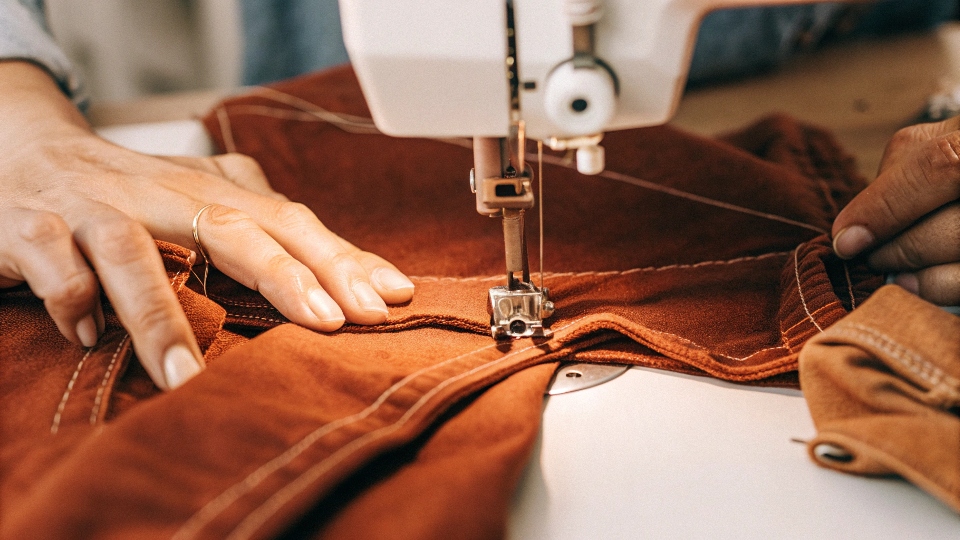 A sewing machine altering the seam of a pair of jeans