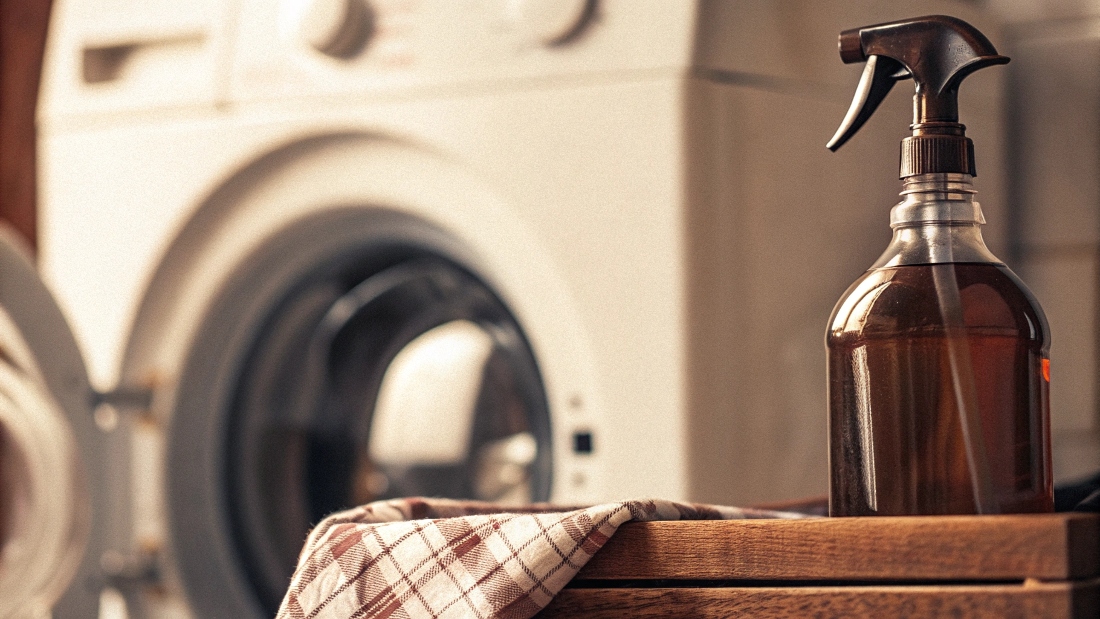 A bottle of vinegar and a box of baking soda next to a washing machine.