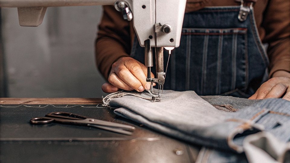 Craftsmanship in Designer Jeans Manufacturing A detailed shot of a skilled worker sewing a complex stitch on a pair of high-end jeans