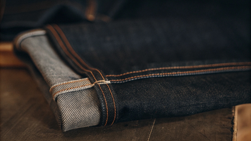 A marketplace booth displaying stacks of denim jeans for wholesale buyers