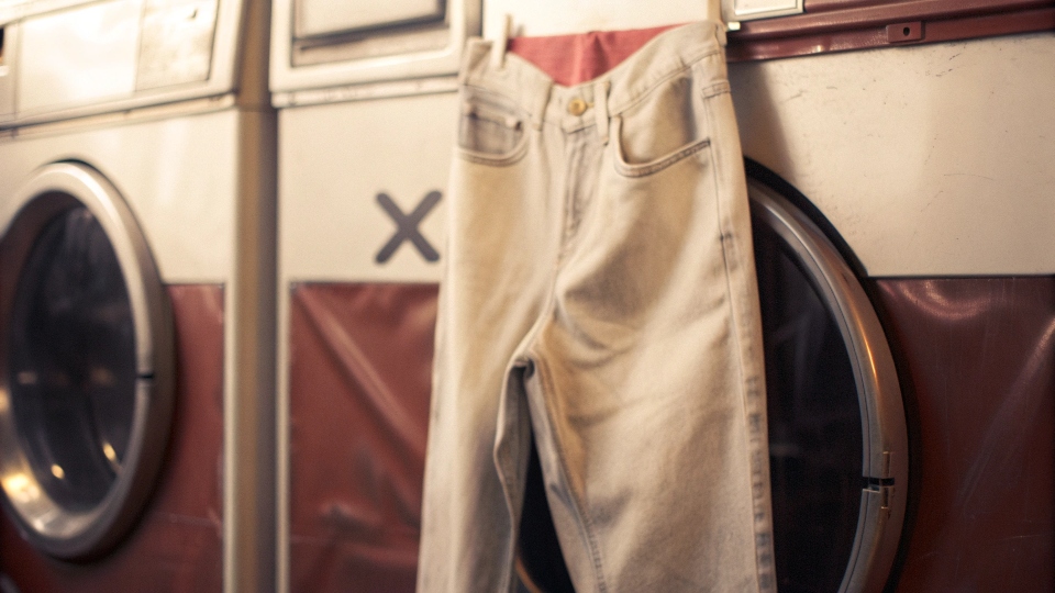 A pair of perfectly worn-in jeans hanging next to a washing machine with a large "X" over it
