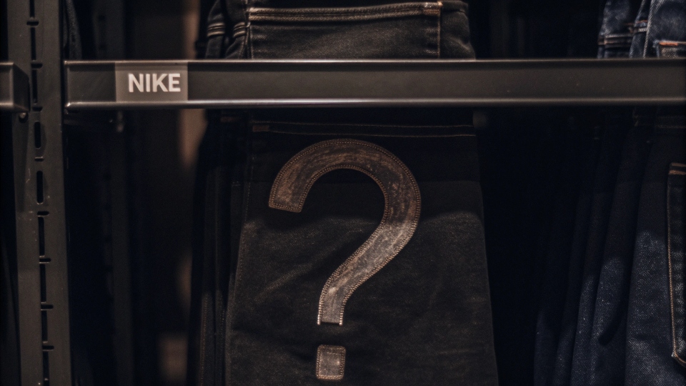 A pair of Nike jeans on a store shelf with a large, skeptical question mark placed over them