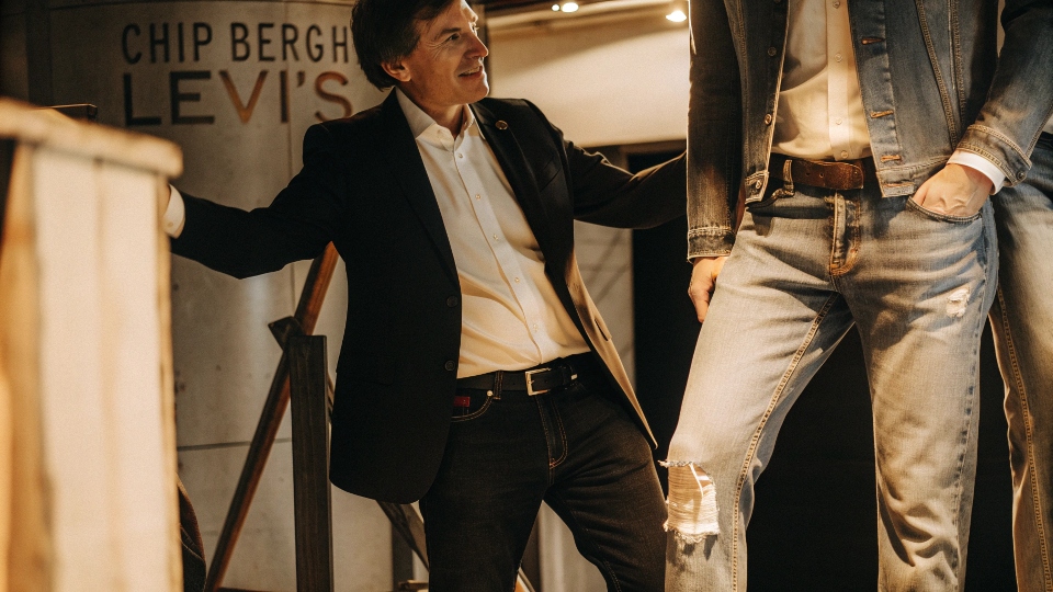 A portrait of a well-dressed executive next to a dedicated denim enthusiast showing off their faded jeans