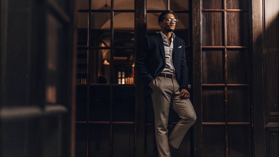 A man looking professional yet approachable, wearing gray chinos, a button-down shirt, and a navy blazer