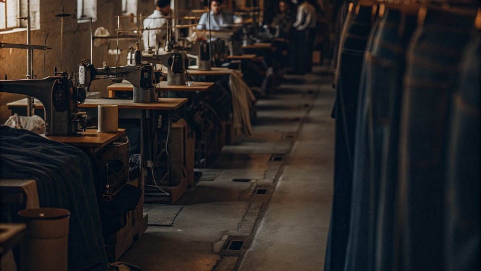 A factory floor with sewing machines in a line, assembling jeans