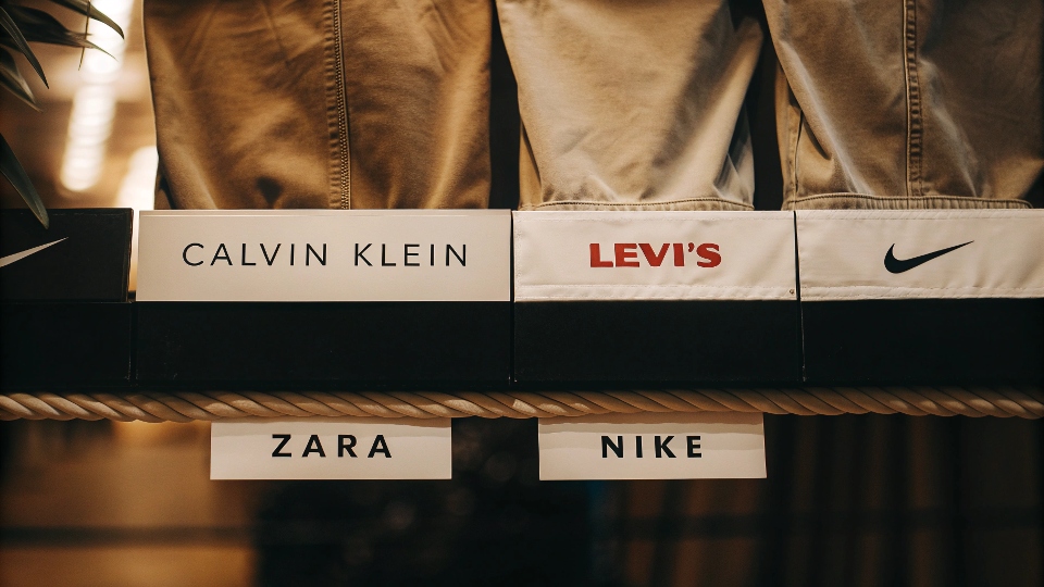 A collage showing the logos of four different major jeans brands like Calvin Klein, Levi's, Zara, and Nike SB