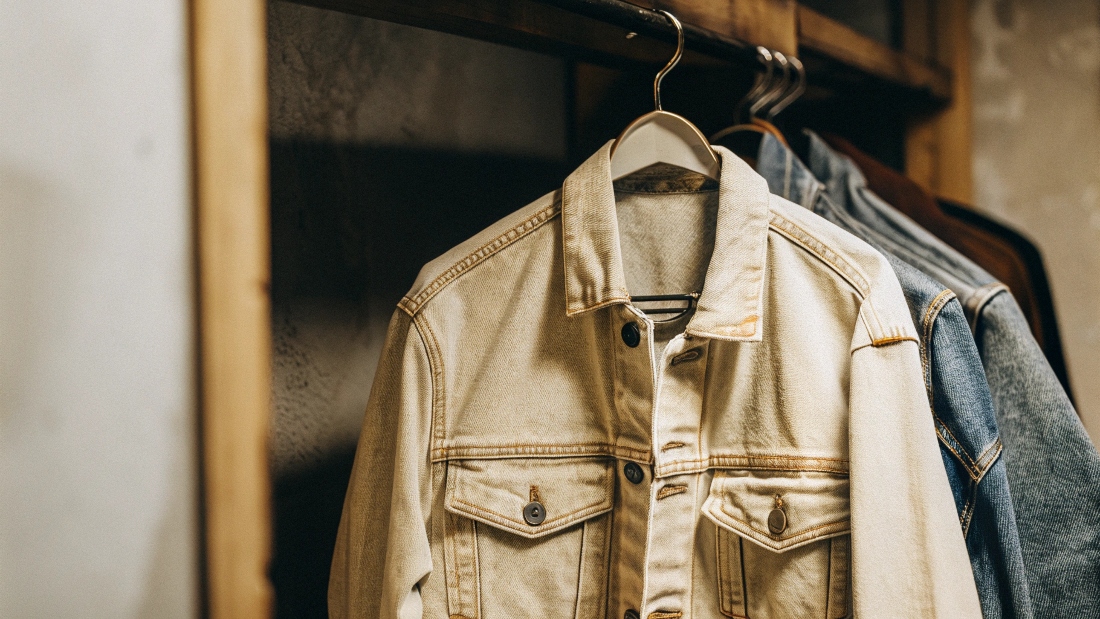 A stylish, soft denim jacket hanging on a hook.