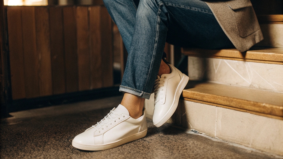A stylish person wearing clean white leather sneakers with perfectly fitted jeans and a casual blazer