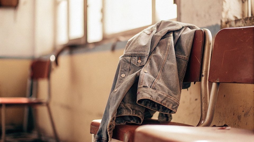 Denim jacket draped over chair after wearing