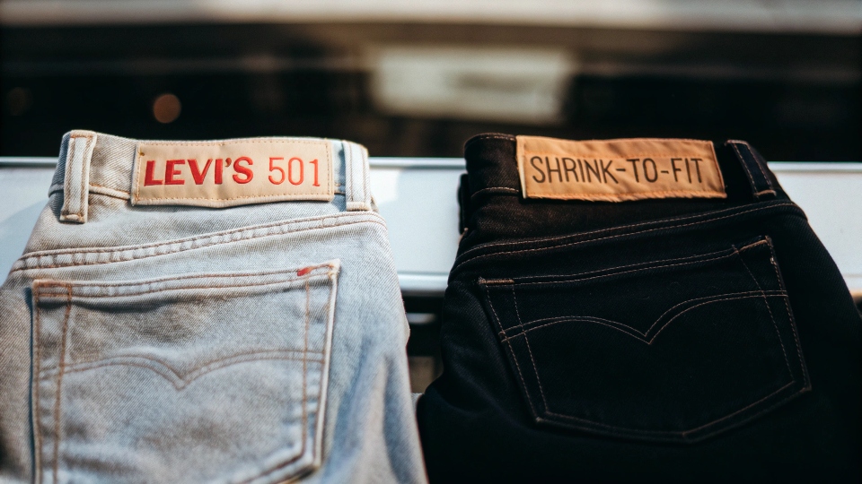 A classic pair of pre-washed Levi's 501 jeans next to a stiff, dark pair of raw "Shrink-to-Fit" 501s