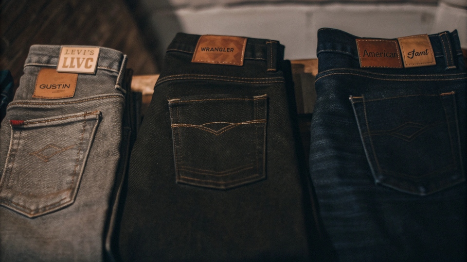 A collection of different American-made jeans laid out, showcasing various brand patches