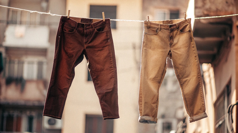 A pair of Uniqlo stretch jeans hanging on a clothesline to air dry