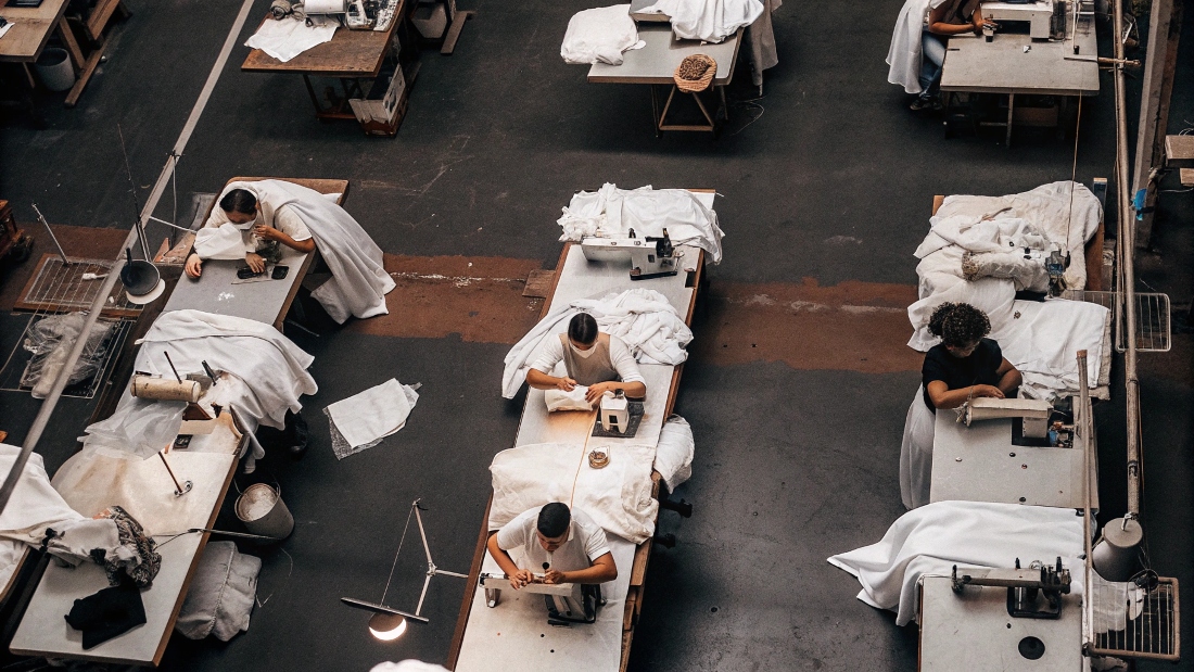 An overhead shot of a busy garment factory floor with workers sewing different types of clothes