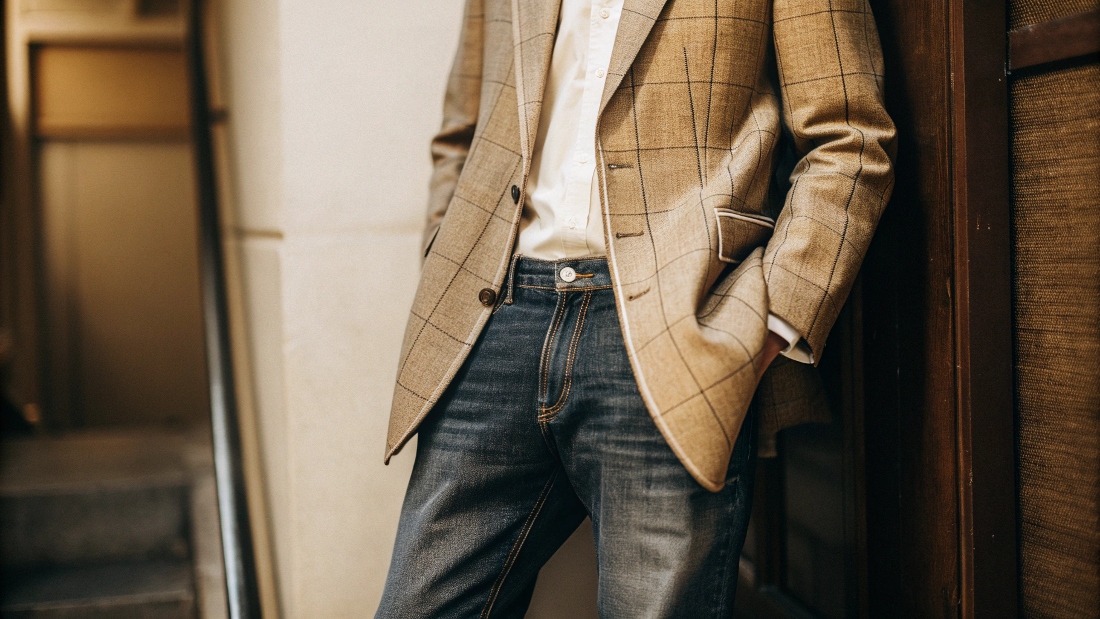 A stylish man looking confident and comfortable pairing a textured sport coat with dark wash denim jeans
