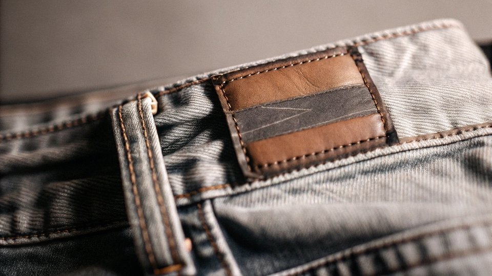 A close-up shot of a leather patch on a pair of jeans that says "Authentic Blue Denim"