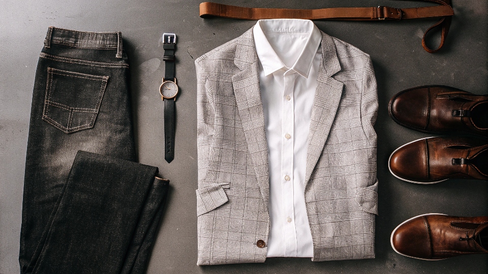 Building a Business Casual Jean Outfit A flat lay of a business casual outfit with dark jeans, a blouse, a blazer, and ankle boots