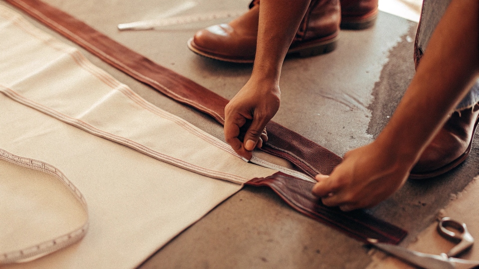 A person marking the hem of their jeans while wearing shoes they plan to pair them with