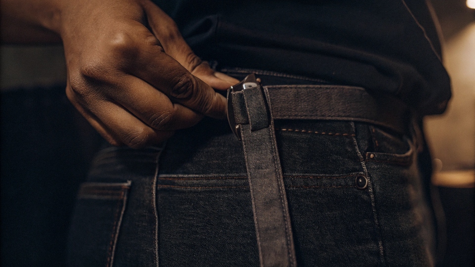 A person inserting a piece of elastic into the back waistband of jeans using a safety pin