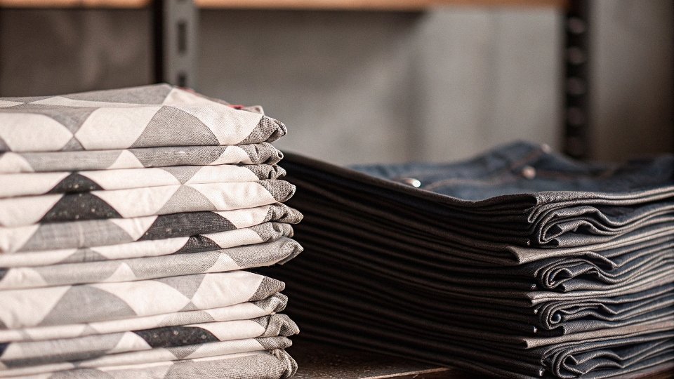 Calculating How Many Jeans for a Quilt A stack of blue jeans next to a pile of neatly cut denim squares ready for a quilt