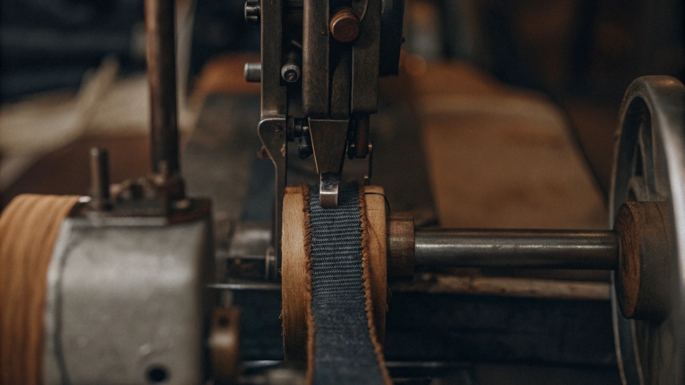 Industrial sewing machine for jeans An industrial sewing machine in a factory setting, easily sewing through a thick denim waistband