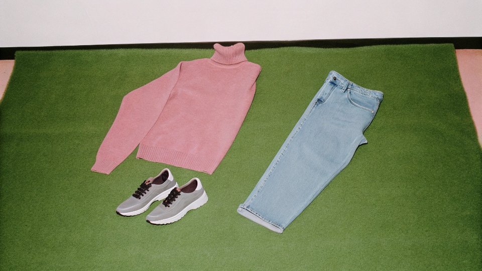 Steve Jobs' Signature Uniform A flat-lay image showing a black turtleneck sweater, blue jeans, and gray sneakers