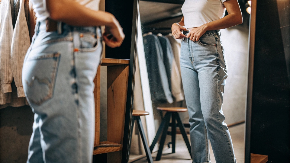Trying on New Jeans for the Perfect Fit A person trying on new jeans in a fitting room, checking the fit in a mirror
