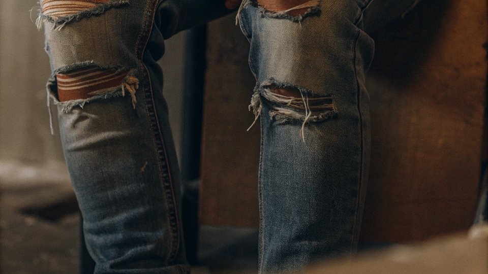 A close-up shot showing thinning, distressed fabric on a pair of heavily bleached jeans