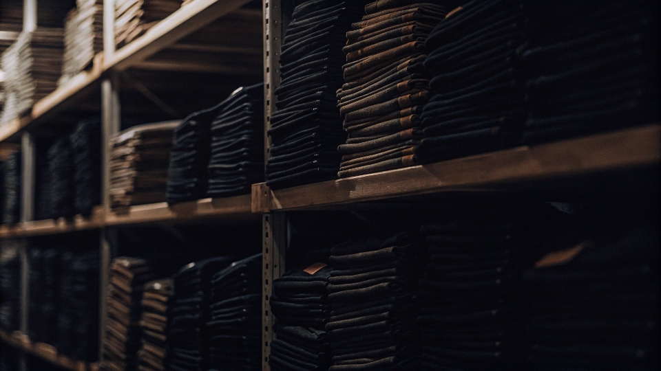 A warehouse shelf packed with boxes of jeans, illustrating inventory management