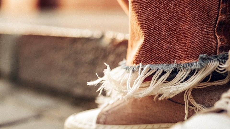 A close-up of a perfectly frayed jean hem, showing the fraying has stopped