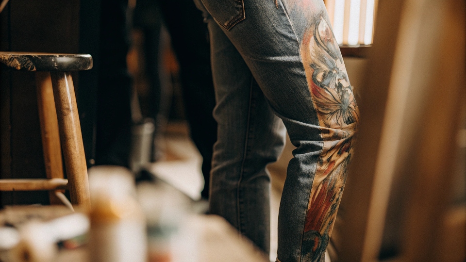 A close-up of vibrant, detailed painting on the leg of a pair of senior jeans