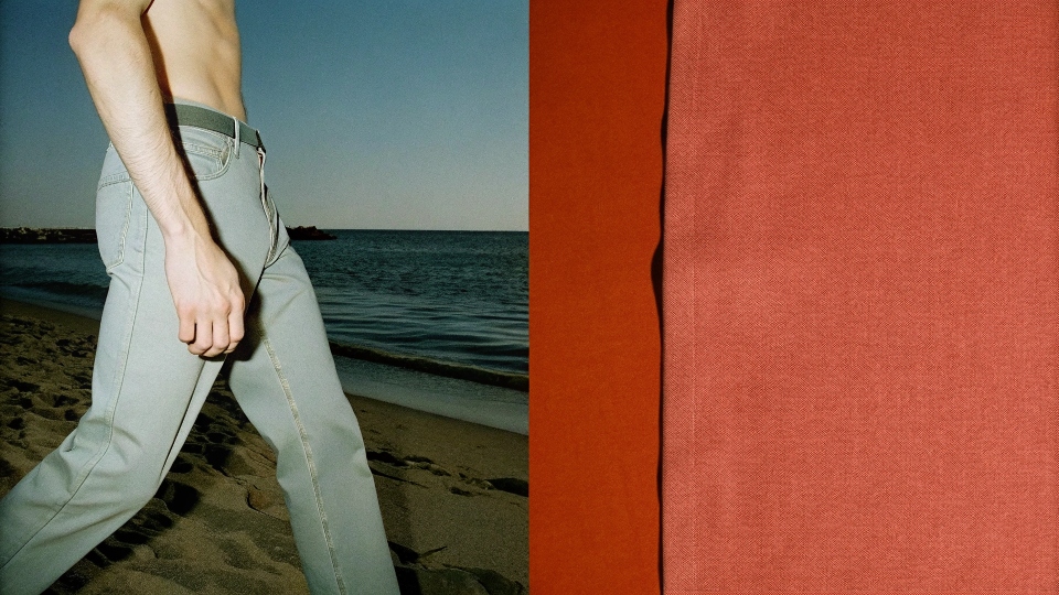 Best Lightweight Jeans for Summer Wear A man wearing light-colored, lightweight jeans walking on a beach in summer