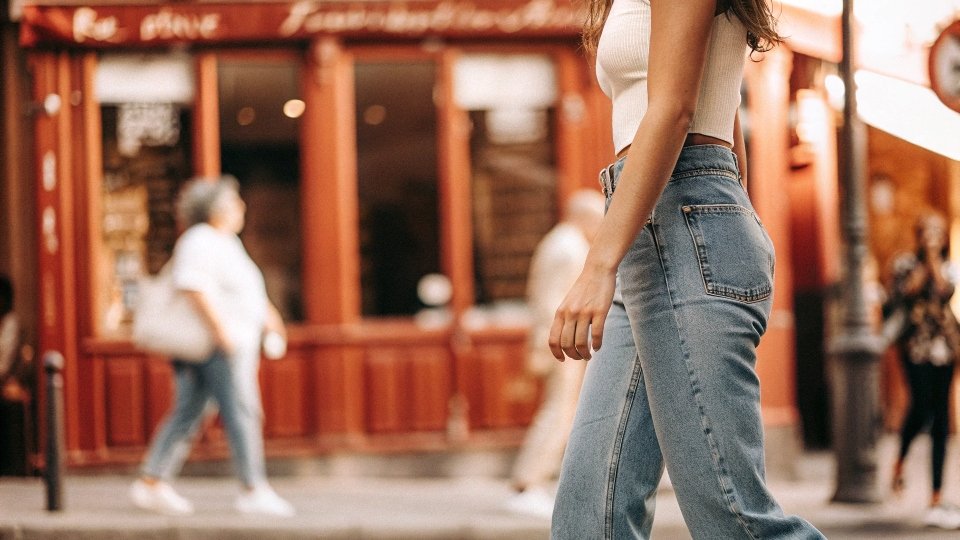 A stylish person walking on a street in Paris wearing classic blue jeans