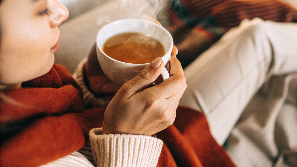 Natural Remedies for Debloating A person sipping a cup of herbal tea and looking relaxed