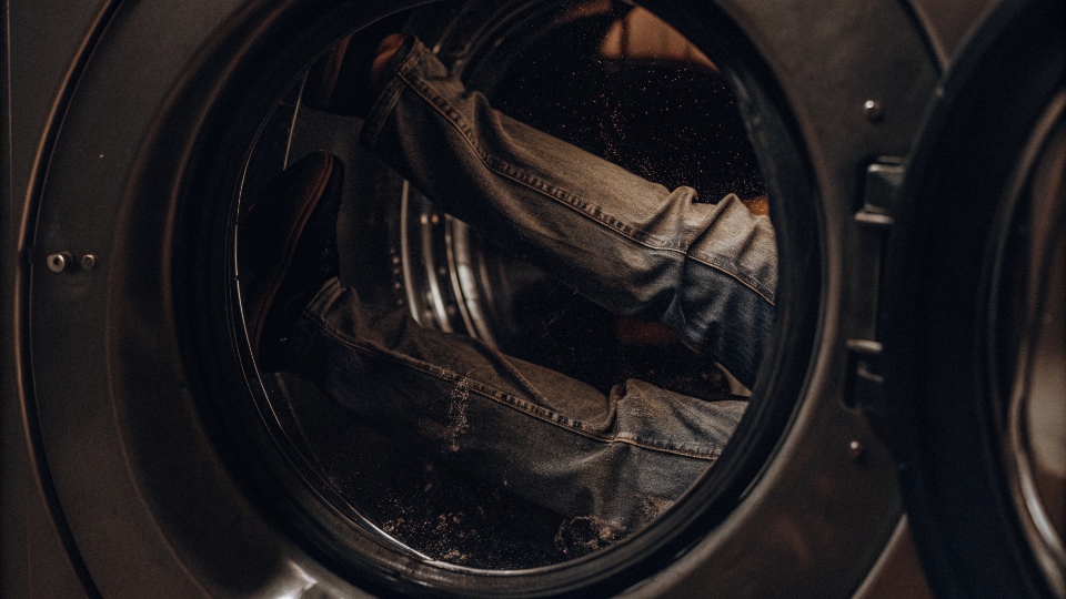 Jeans tumbling inside a washing machine, simulating the process of breaking them in