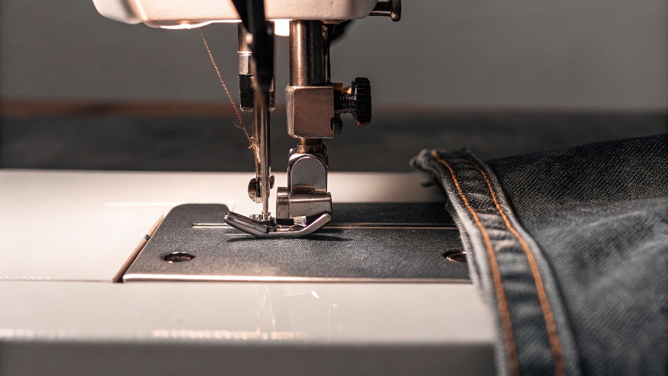 Sewing Overalls on a Machine A sewing machine in action, topstitching the edge of a denim bib for a professional look