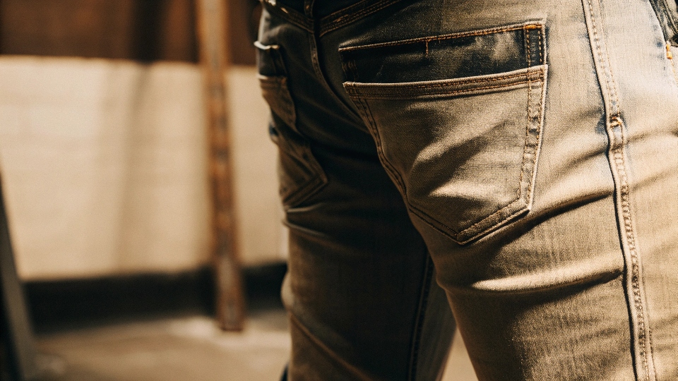 A close-up macro shot of the thick, bold "Super T" stitch on a pair of True Religion jeans