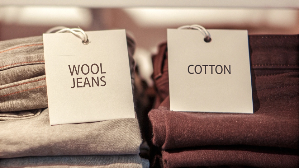Cost Comparison of Wool and Cotton Jeans A price tag showing a high price on a pair of wool jeans next to a lower priced cotton pair