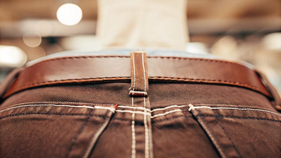A close-up of the back of a pair of jeans, showing the center seam where it can be let out